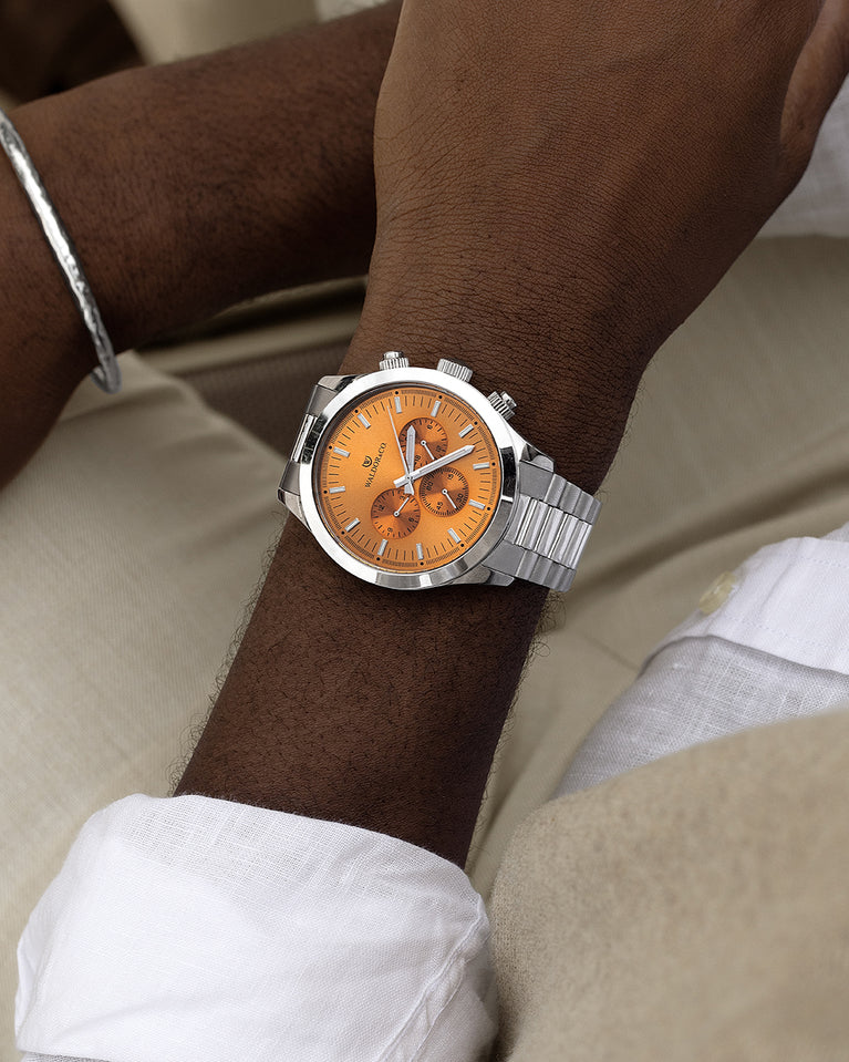 A round mens watch in rhodium-plated silver from Waldor & Co. with orange sunray dial and a second hand. Seiko movement. The model is Chrono 44 Como 44mm.