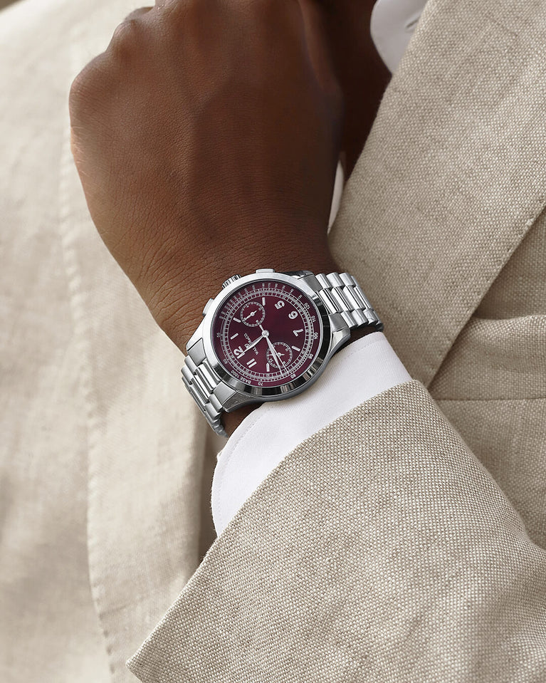 A round mens watch in rhodium-plated silver from Waldor & Co. with a burgundy colored sunray dial and a second hand. Seiko movement. The model is Chrono 39 Porto Cervo.