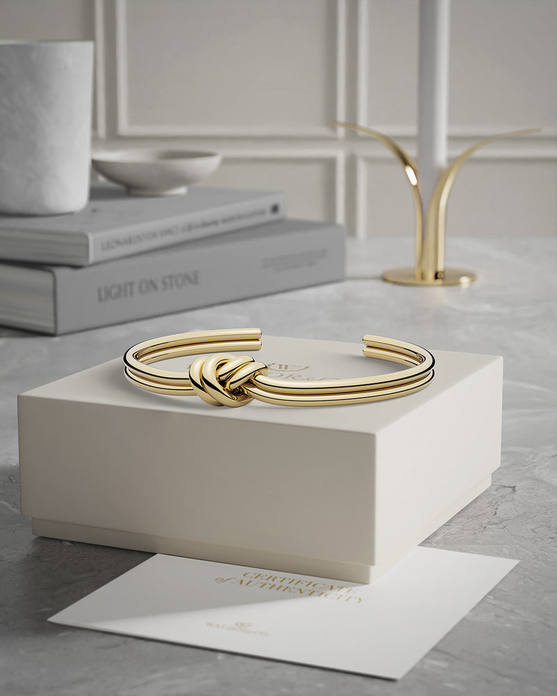 A Bangle in 14k-gold plated 316L stainless steel from Waldor & Co. One size. The model is Dual Knot Bangle Polished.