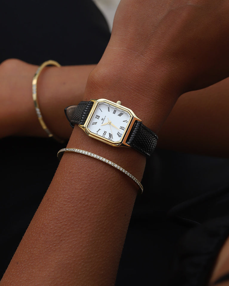 A square womens watch in 22k gold from Waldor & Co. with white Diamond Cut Sapphire Crystal glass dial. Strap in black Genuine leather. Seiko movement. The model is Eternal 22 Varenna. 