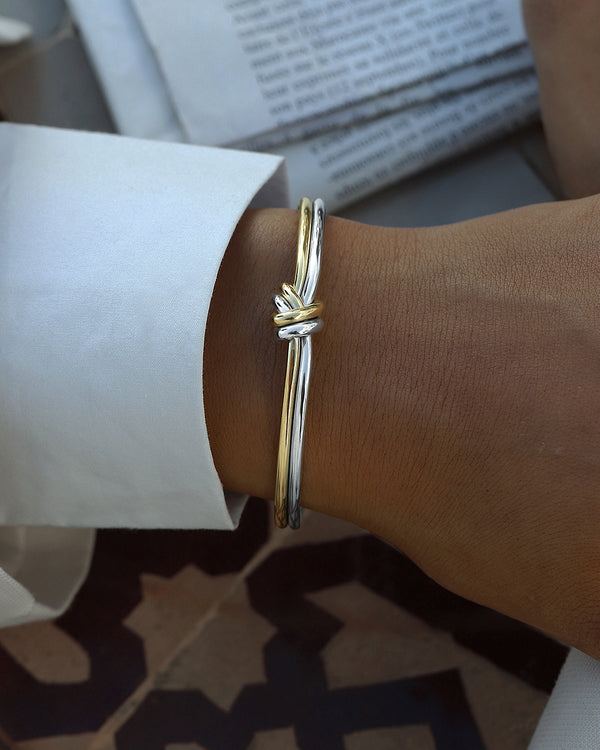 A Bangle in 14k-gold plated and silver polished 316L stainless steel from Waldor & Co. One size. The model is Dual Knot Bangle Polished.