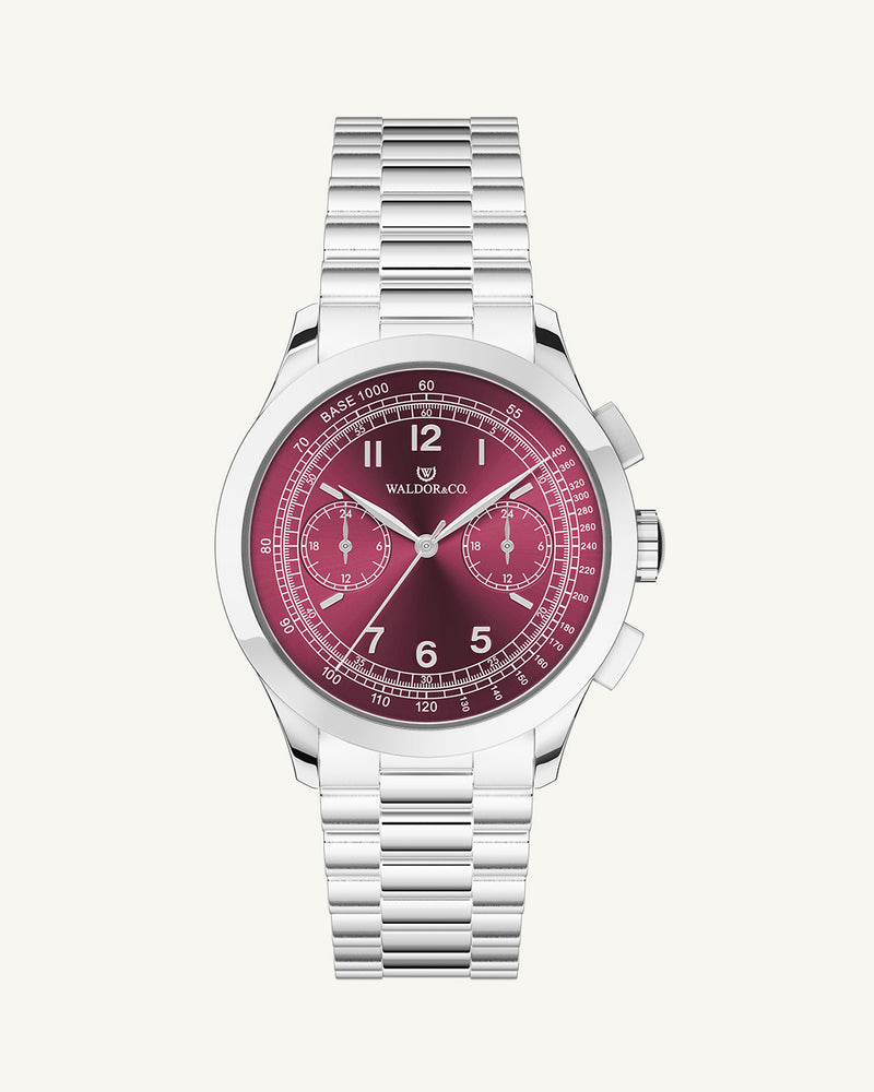 A round mens watch in rhodium-plated silver from Waldor & Co. with a burgundy colored sunray dial and a second hand. Seiko movement. The model is Chrono 39 Porto Cervo.