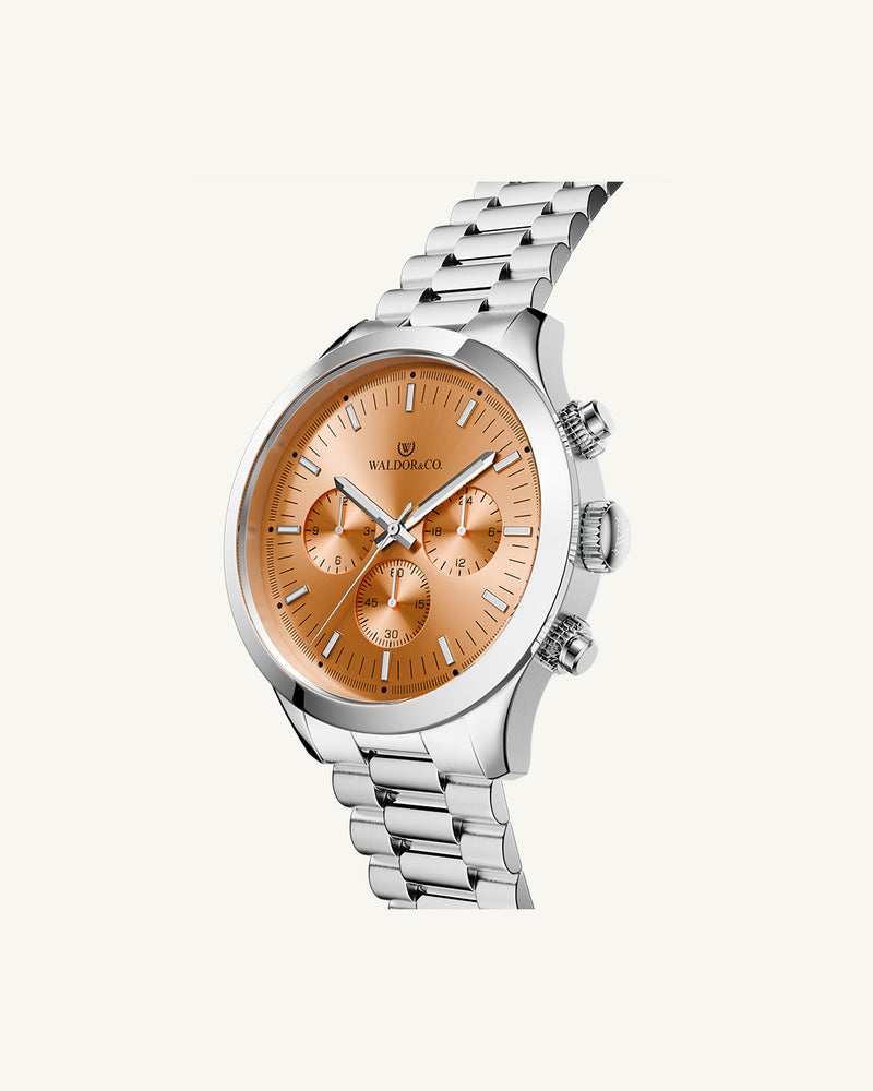 A round mens watch in rhodium-plated silver from Waldor & Co. with orange sunray dial and a second hand. Seiko movement. The model is Chrono 44 Como 44mm.