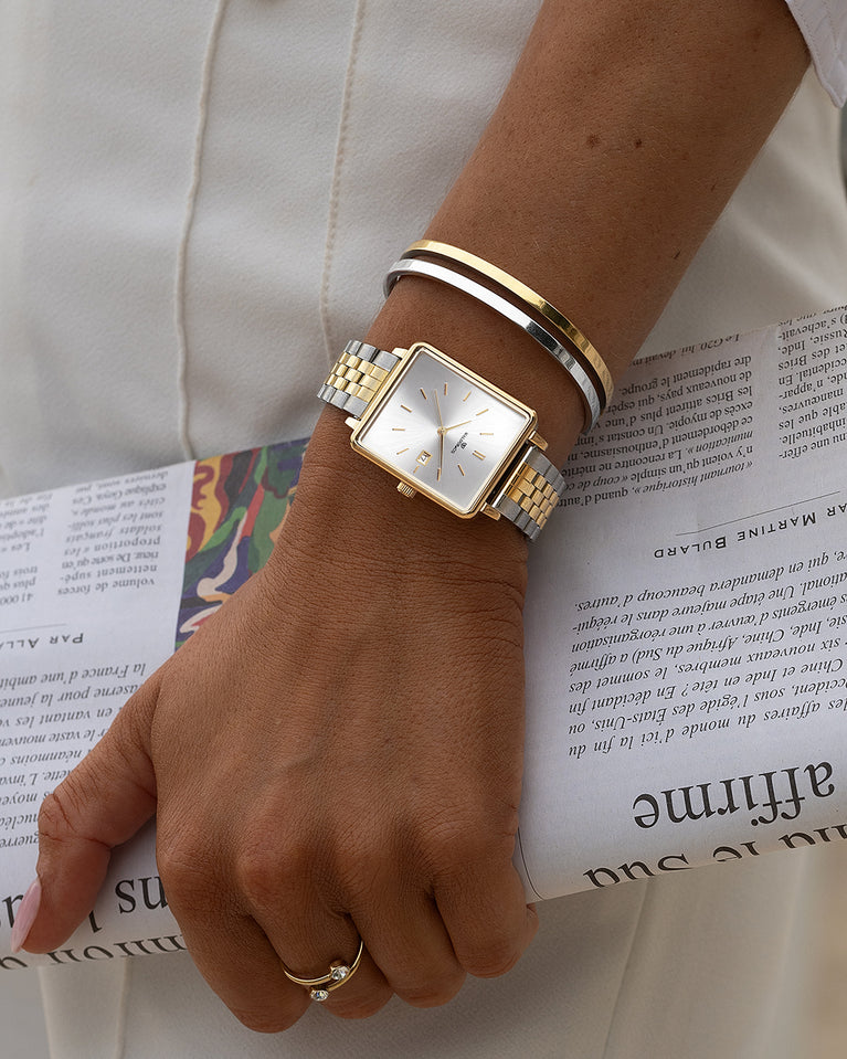 A square womens watch in silver and 14k gold from Waldor & Co. with silver sunray dial and a second hand. Seiko movement. The model is Delight 32 Chelsea 28x32mm.