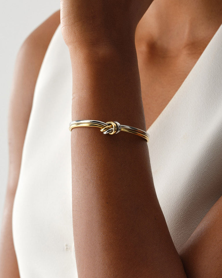 A Bangle in 14k-gold plated and silver polished 316L stainless steel from Waldor & Co. One size. The model is Dual Knot Bangle Polished.