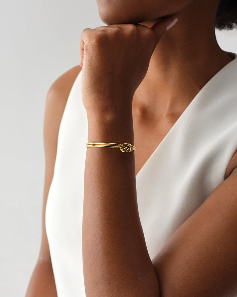 A Bangle in 14k-gold plated 316L stainless steel from Waldor & Co. One size. The model is Dual Knot Bangle Polished.