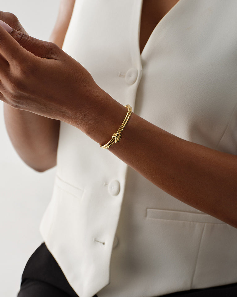 A Bangle in 14k-gold plated 316L stainless steel from Waldor & Co. One size. The model is Dual Knot Bangle Polished.