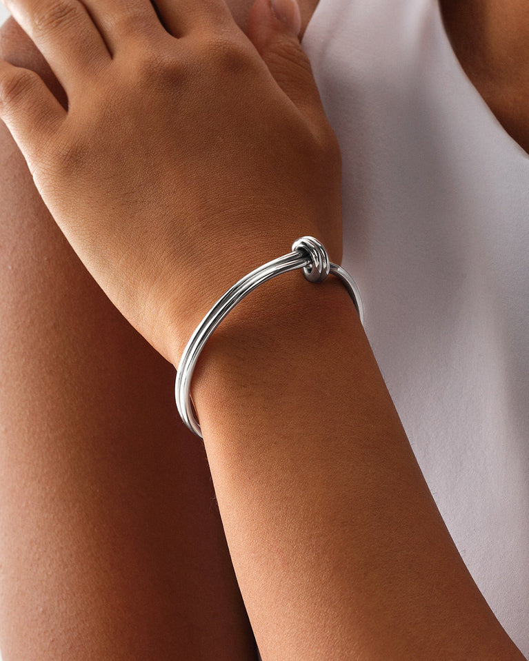 A Bangle Bracelet in polished Silver plated-316L stainless steel from Waldor & Co. The model is Dual Knot Bangle Polished.