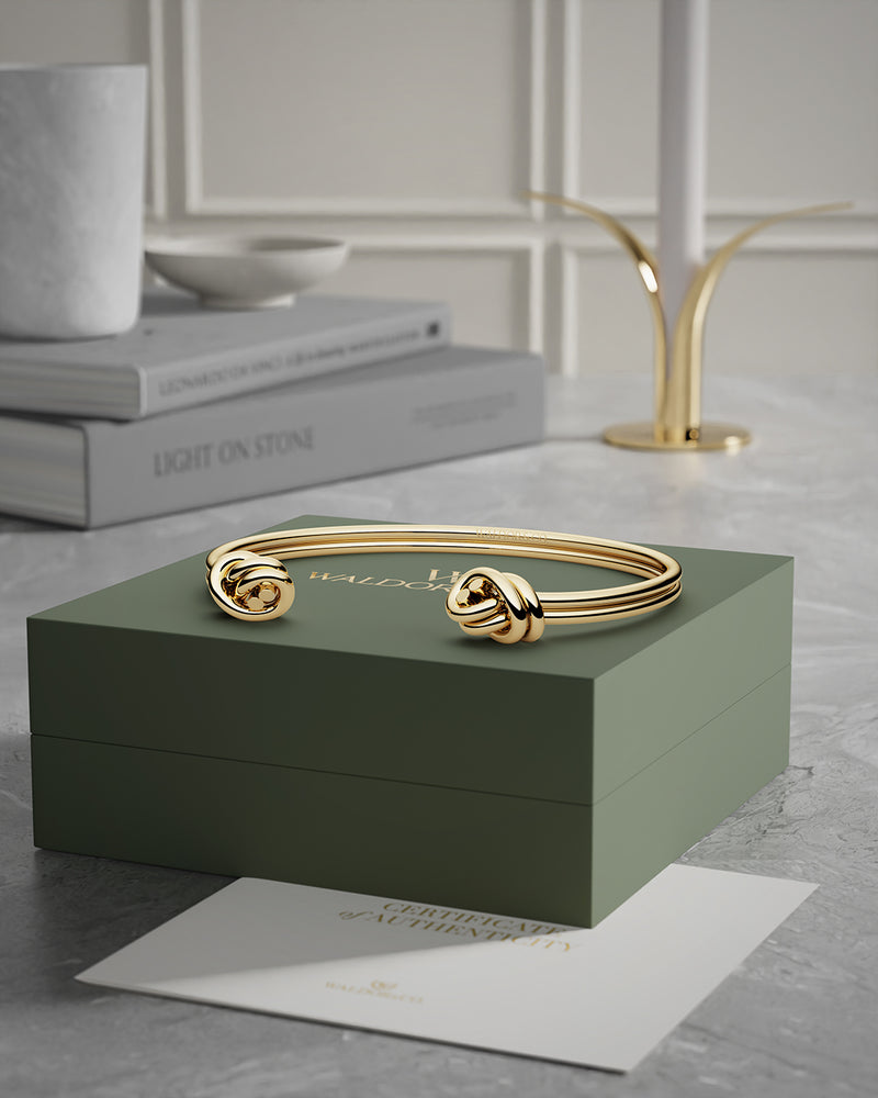 A Bangle in 14k-gold plated 316L stainless steel from Waldor & Co. One size. The model is Dual Knot Twin Bangle Polished.