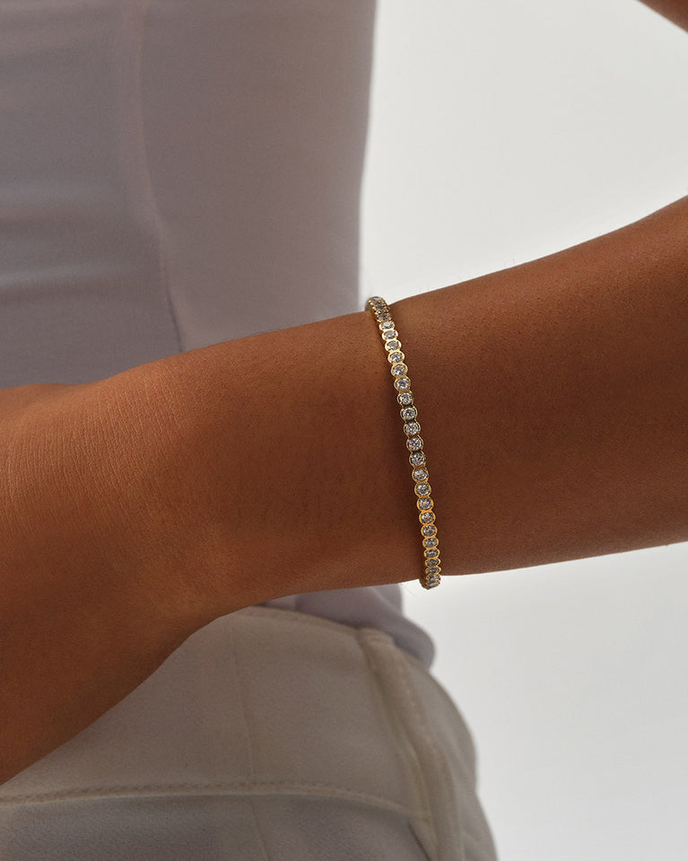 A polished stainless steel bangle in 14k gold from Waldor & Co. One size. The model is Grace Bangle Polished.