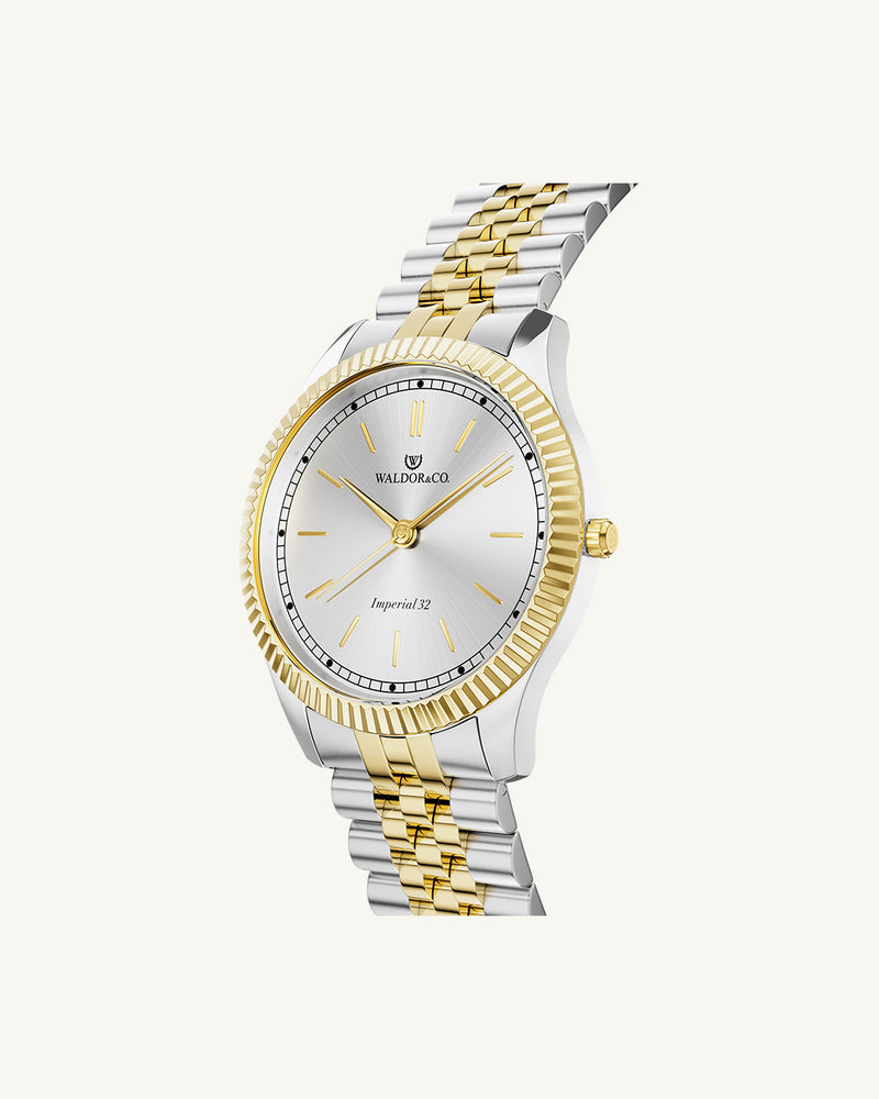 A round womens watch in silver and 22k gold from Waldor & Co. with silver sunray dial and a second hand. Seiko movement. The model is Imperial 32 Positano 32mm.