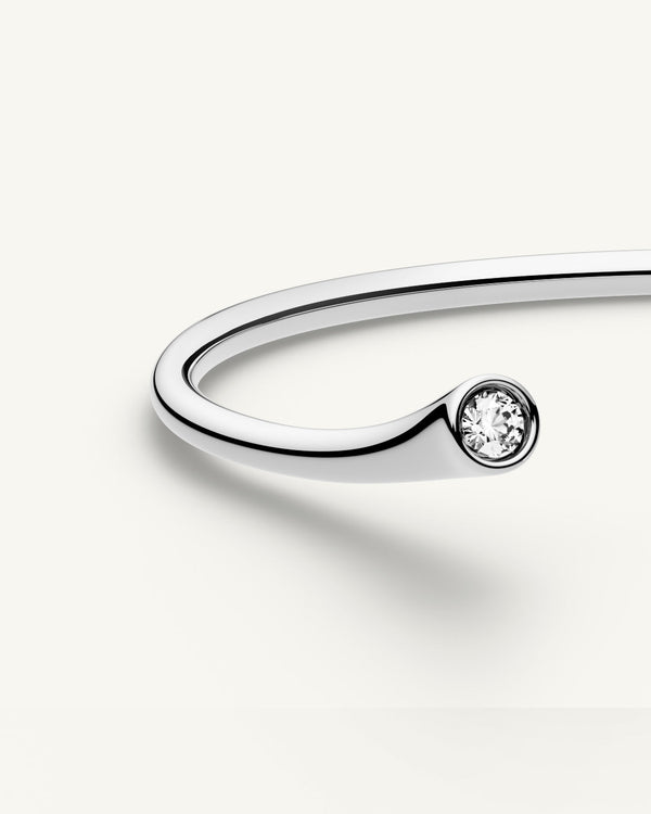 A polished stainless steel bangle from Waldor & Co. One size. The model is Delight Bangle.